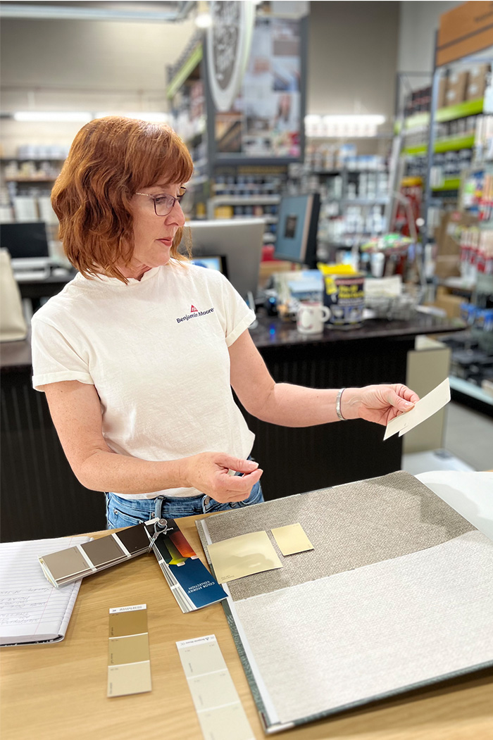 Photo of Leslie working at Excelsior Paint and Design standing in the benjamin moore and fine paints of europe paint department. 